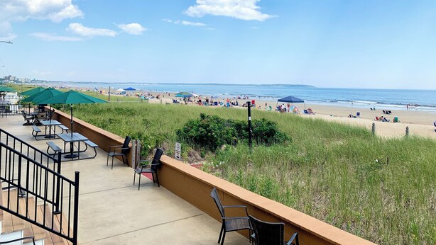 Un patio frente a la playa con mobiliario exterior y vistas a la playa.