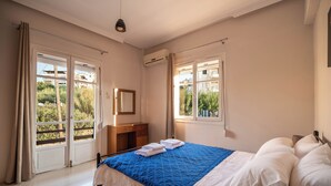 A bedroom with a bed, a dresser, and a window with curtains. - SEA GEM APARTMENTS steps from the sand (Chania)