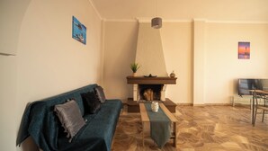 A living room with a sofa, a fireplace, a TV, and a patterned floor. - SEA GEM APARTMENTS steps from the sand (Chania)