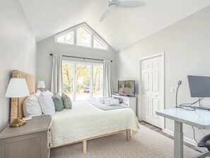 Un dormitorio con cama, escritorio, televisor y ventilador de techo.