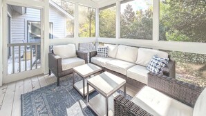 A covered porch with wicker furniture, a white sofa, and a ceiling fan. - Quiet Sea Pines Home: Screened Porch + Beach Gear (Hilton Head Island)