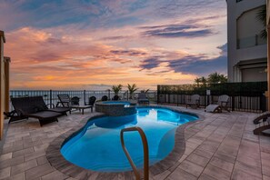 Una piscina con sillas de descanso, un jacuzzi y vistas al atardecer.