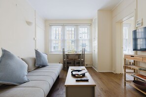 Ein modernes Wohnzimmer mit einer Couch, einem Couchtisch, einem Fernseher und einem Essbereich mit Tisch und Stühlen.