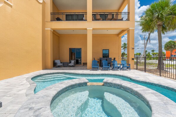 A swimming pool with a hot tub, outdoor seating, and a balcony with railings. - Sunset Siesta (Fort Myers Beach)