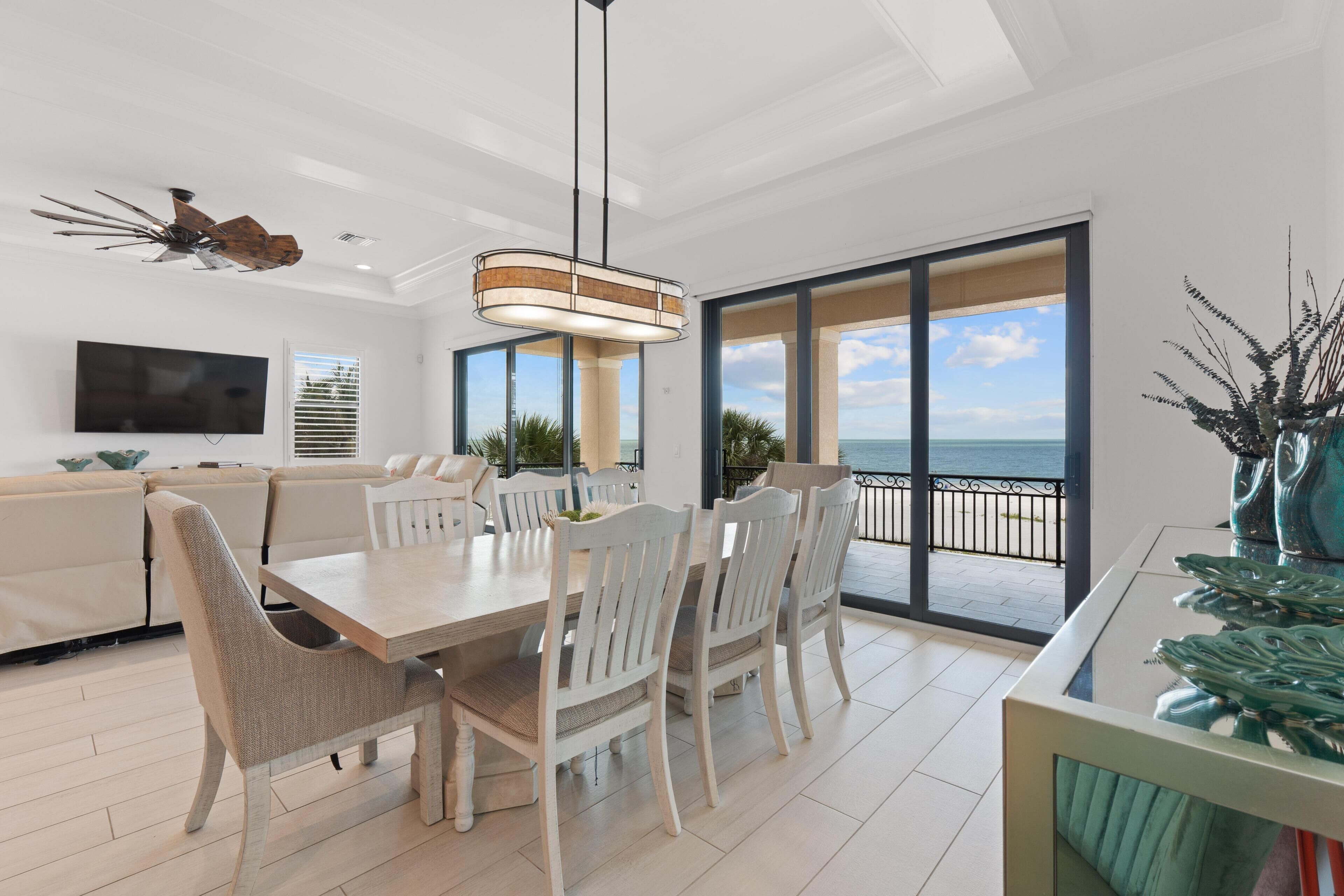 A modern living room with a dining area, large windows, and a view of the ocean.