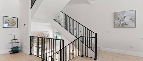 Un interior moderno con una escalera, una obra de arte enmarcada y una planta en maceta.