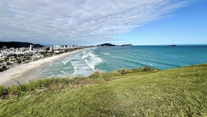A coastal cityscape with a beach, buildings, and a clear sky. - Apartamento Enseada 24 (Guarujá)