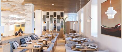 A modern restaurant interior with wooden ceiling, white walls, and a variety of seating arrangements including tables and benches.