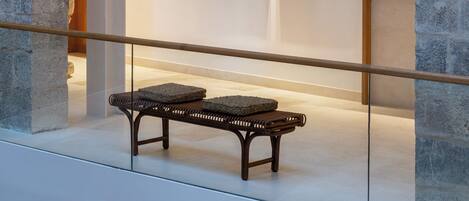 An indoor space with a stone archway, a bench, and two framed artworks on the wall.