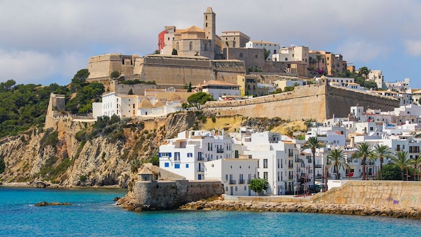 Un pueblo costero con fortificaciones históricas y edificios blancos.