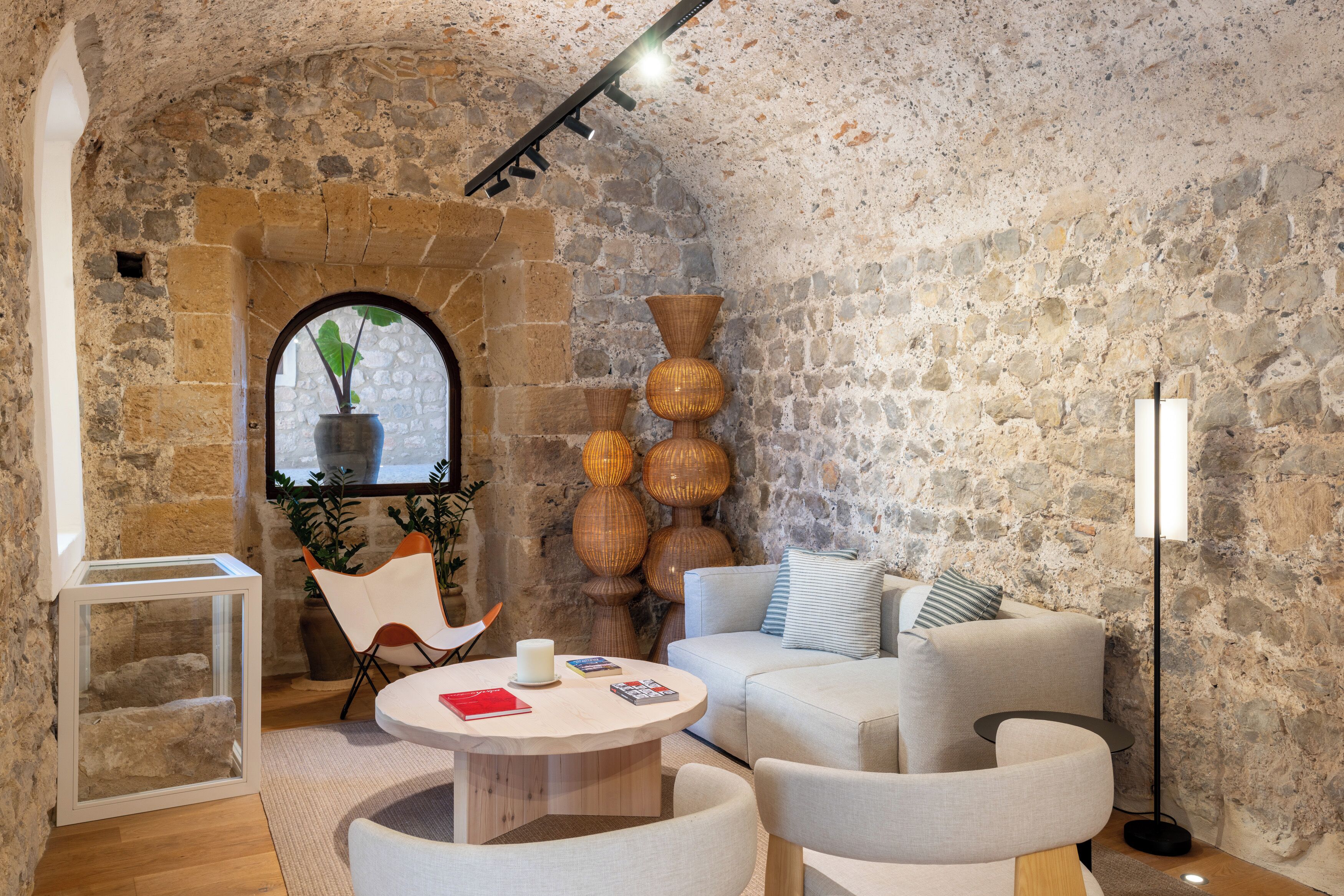 A cozy room with a stone wall, a round wooden table, and a sofa.