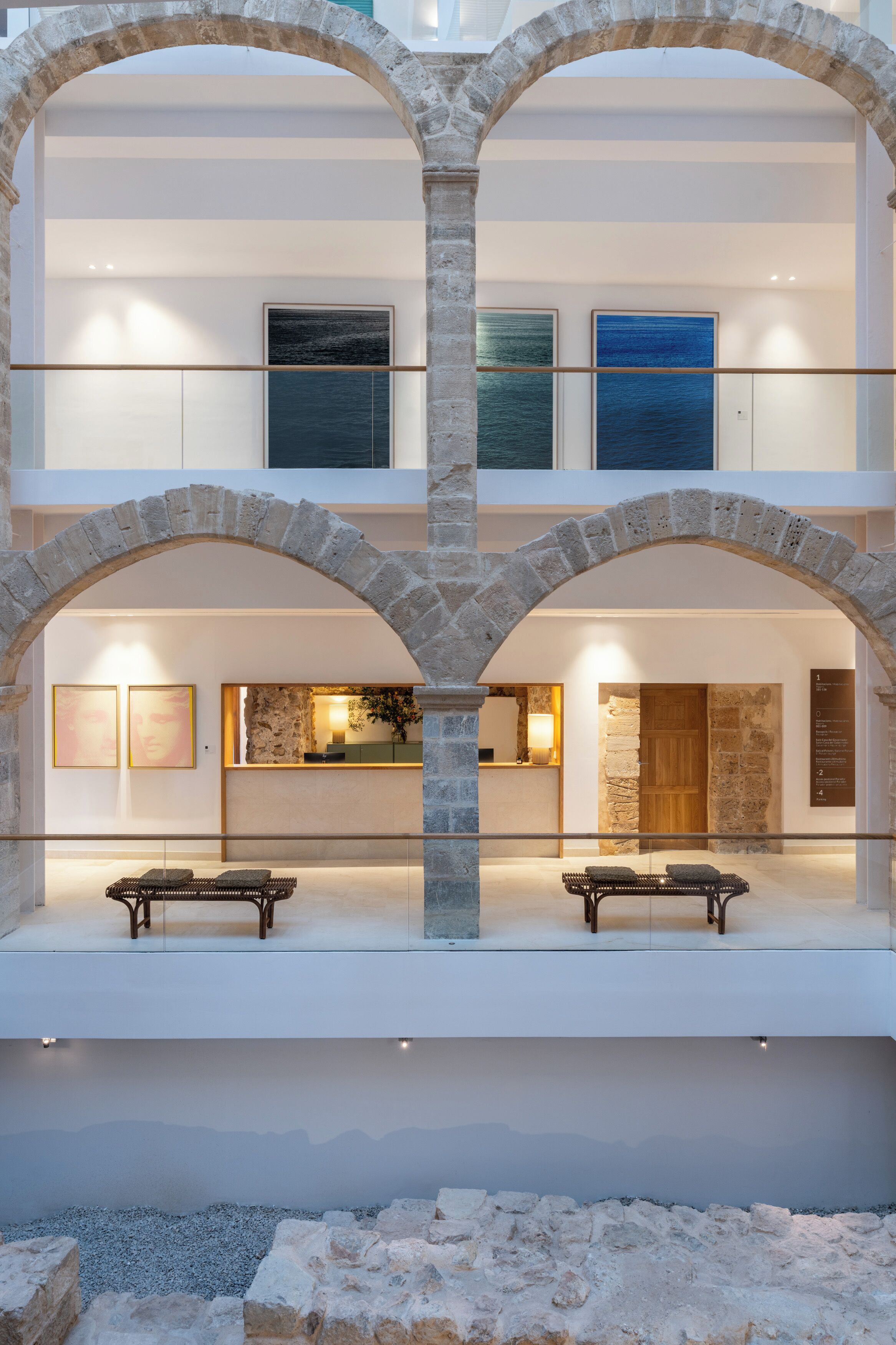 A multi-level hotel lobby with stone arches, a reception desk, and seating areas.