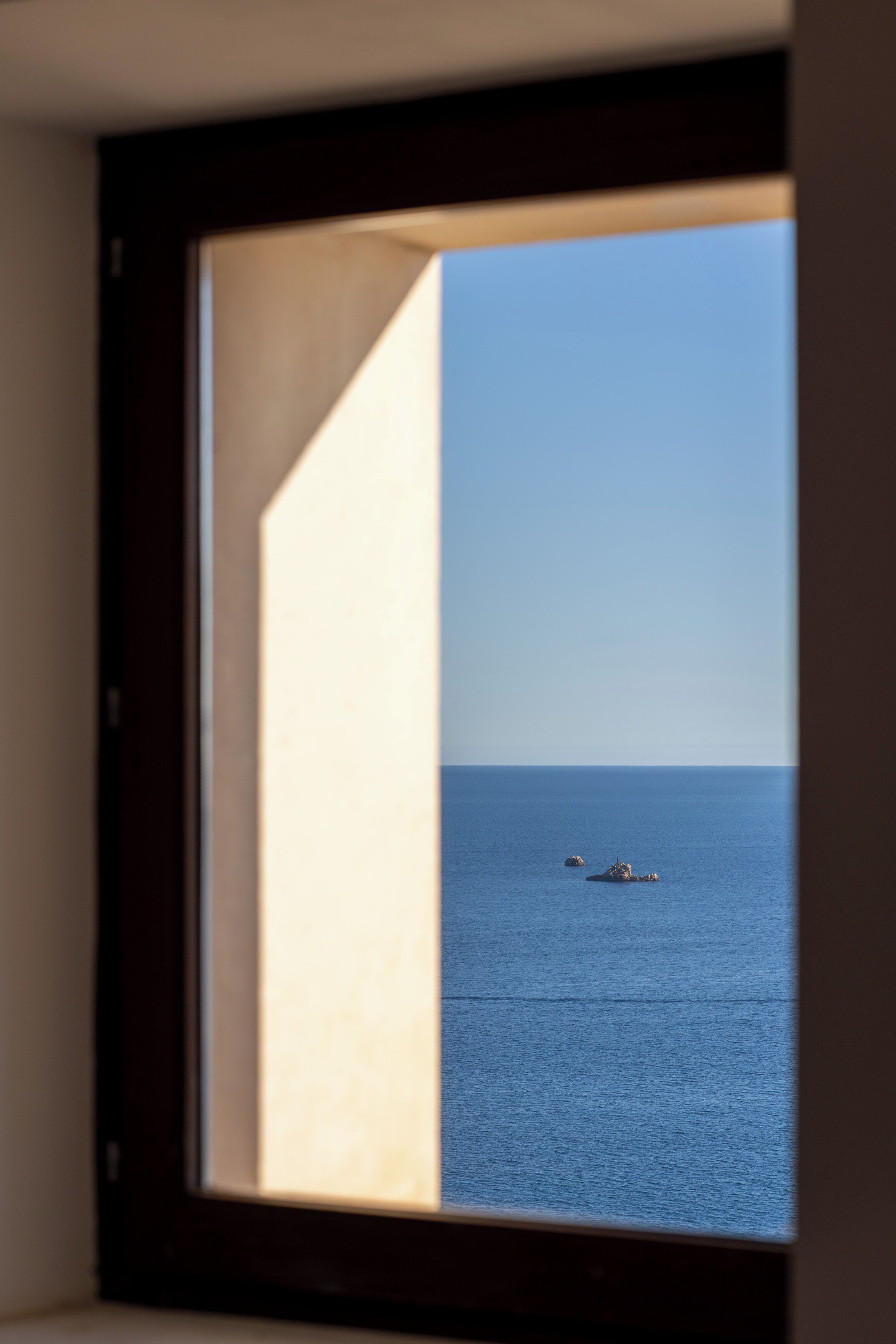 Vista al mar desde una ventana, con cielo despejado.