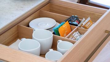 A drawer with white mugs, plates, and food packets.