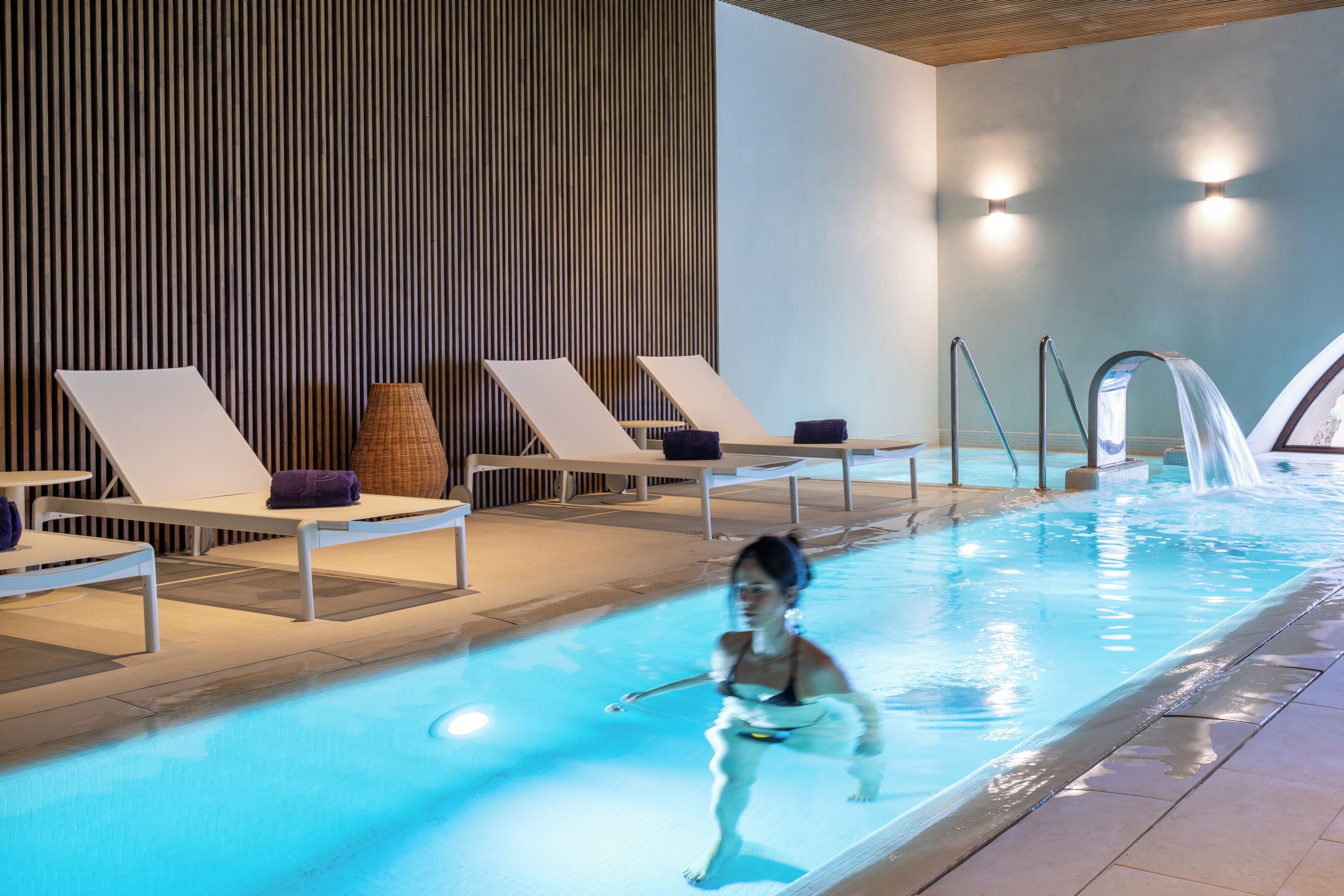 Ein Schwimmbecken mit Liegestühlen und einer Wasserspalt.