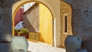 Un arcoado de piedra conduce a un patio con suelo de baldosas y grandes macetas de cerámica.