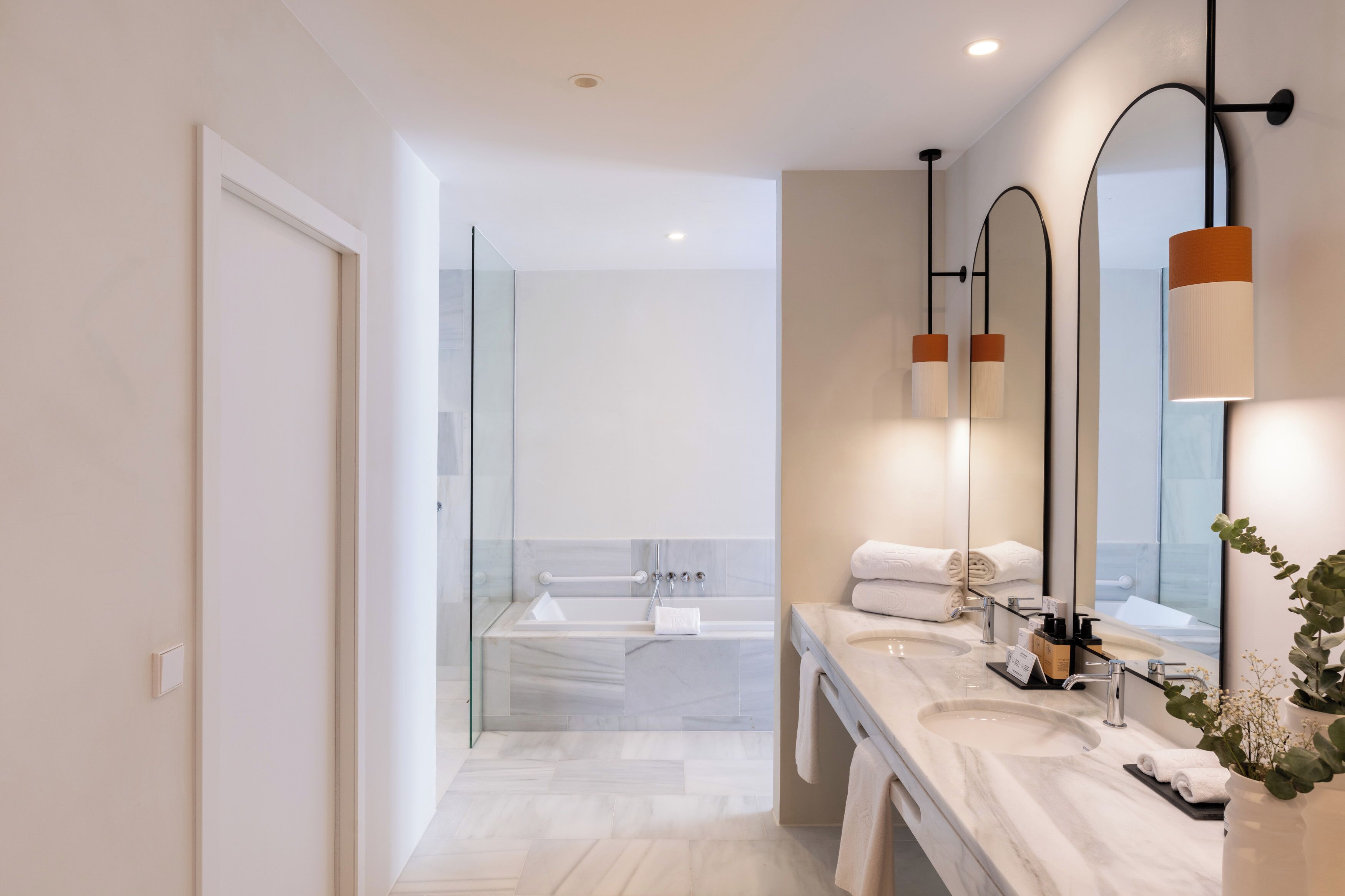 A modern bathroom with a glass shower enclosure, a double sink vanity, and a large mirror.
