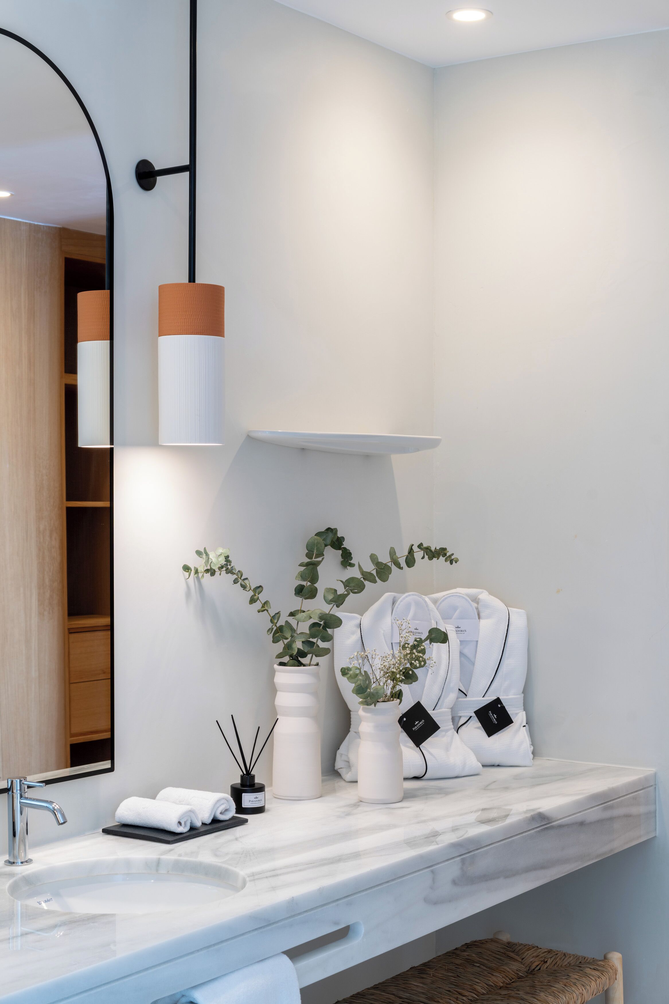 Une salle de bain moderne avec un lavabo blanc, un miroir et une plante en pot.