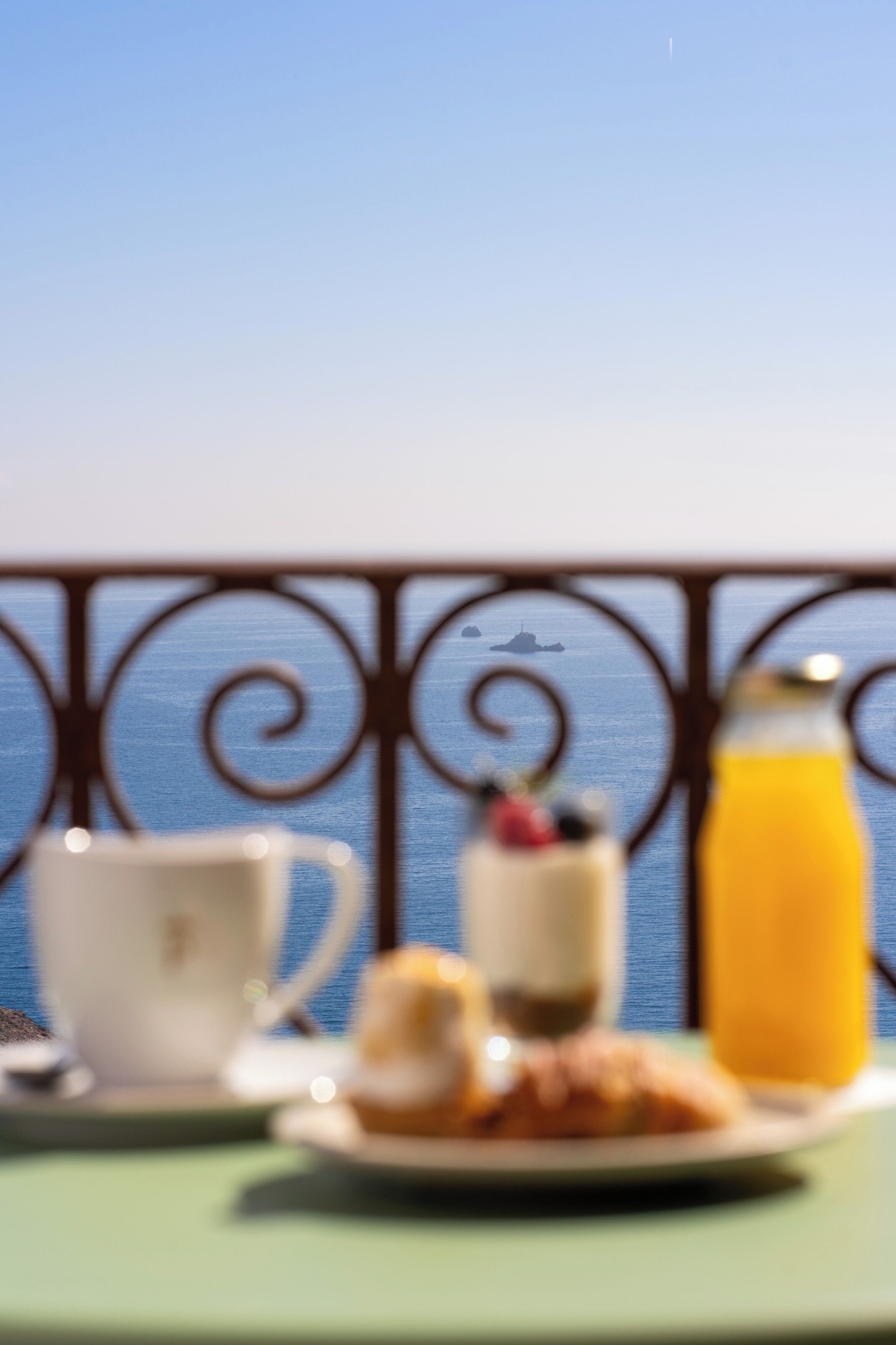 A table with a cup, a glass of orange juice, and a plate with pastries.