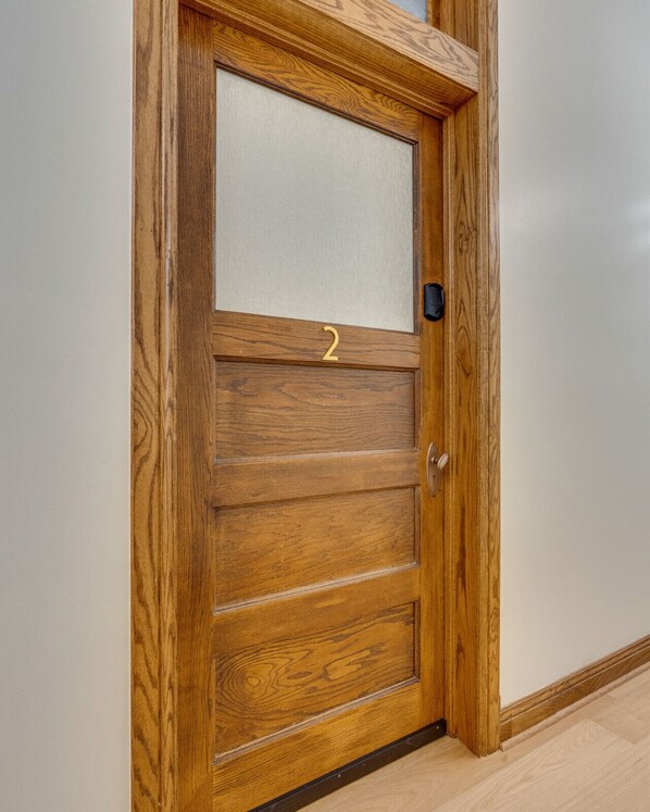 Una puerta de madera con un panel de vidrio satinado y una placa de número de latón.