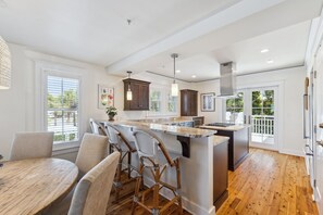 A modern kitchen with a central island, bar stools, and a dining table. - Gulffront WaterColor Condo w/ 6-Seat LSV (Santa Rosa Beach)