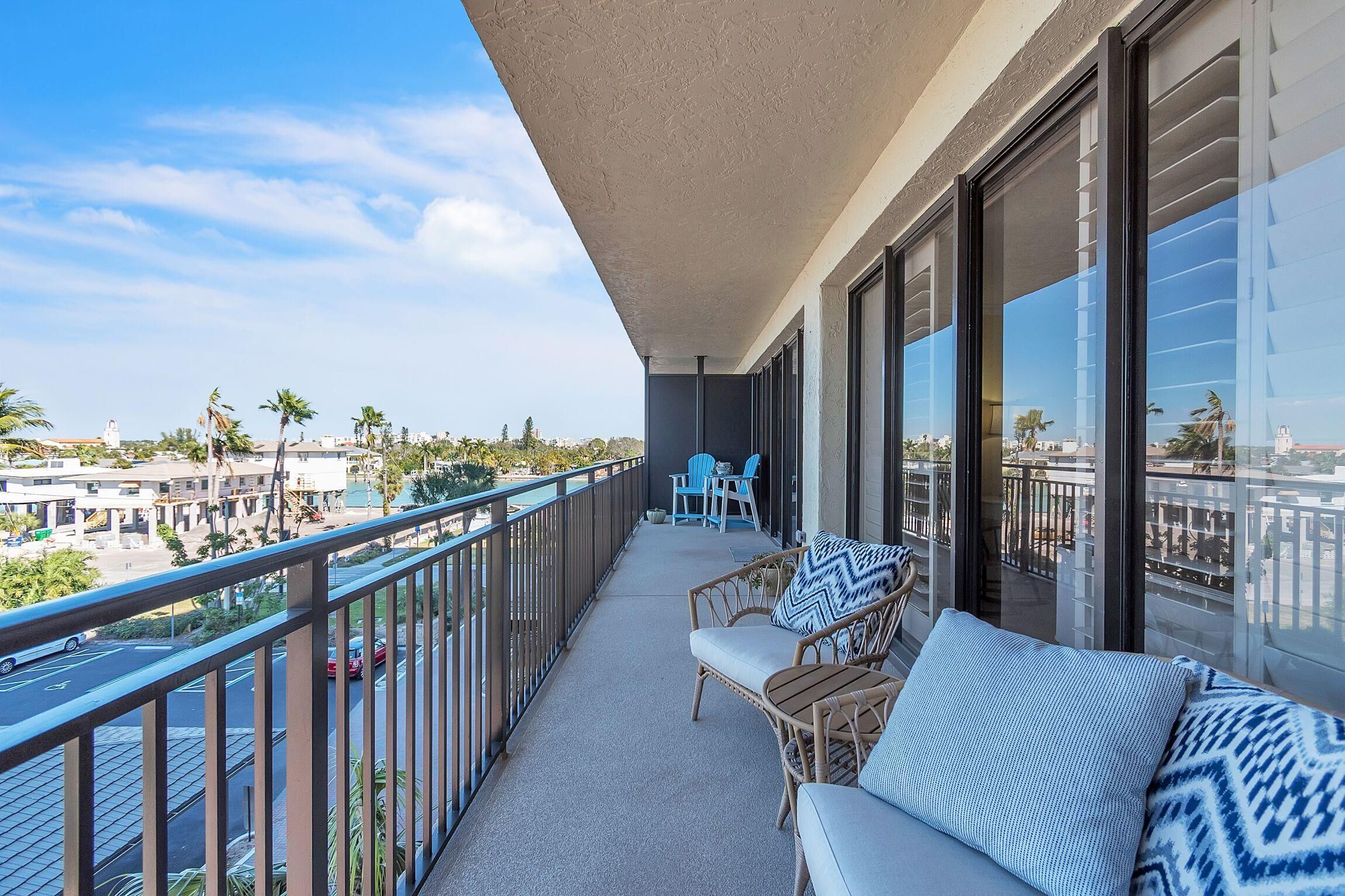 A balcony with wicker furniture, a view of the city, and a clear sky.