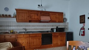 Une cuisine avec des meubles de rangement en bois, un évier, une cuisinière et une table à manger avec des chaises.