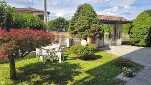 Une cour avec une table et des chaises, un petit jardin et un bâtiment doté d’un toit en tuiles.