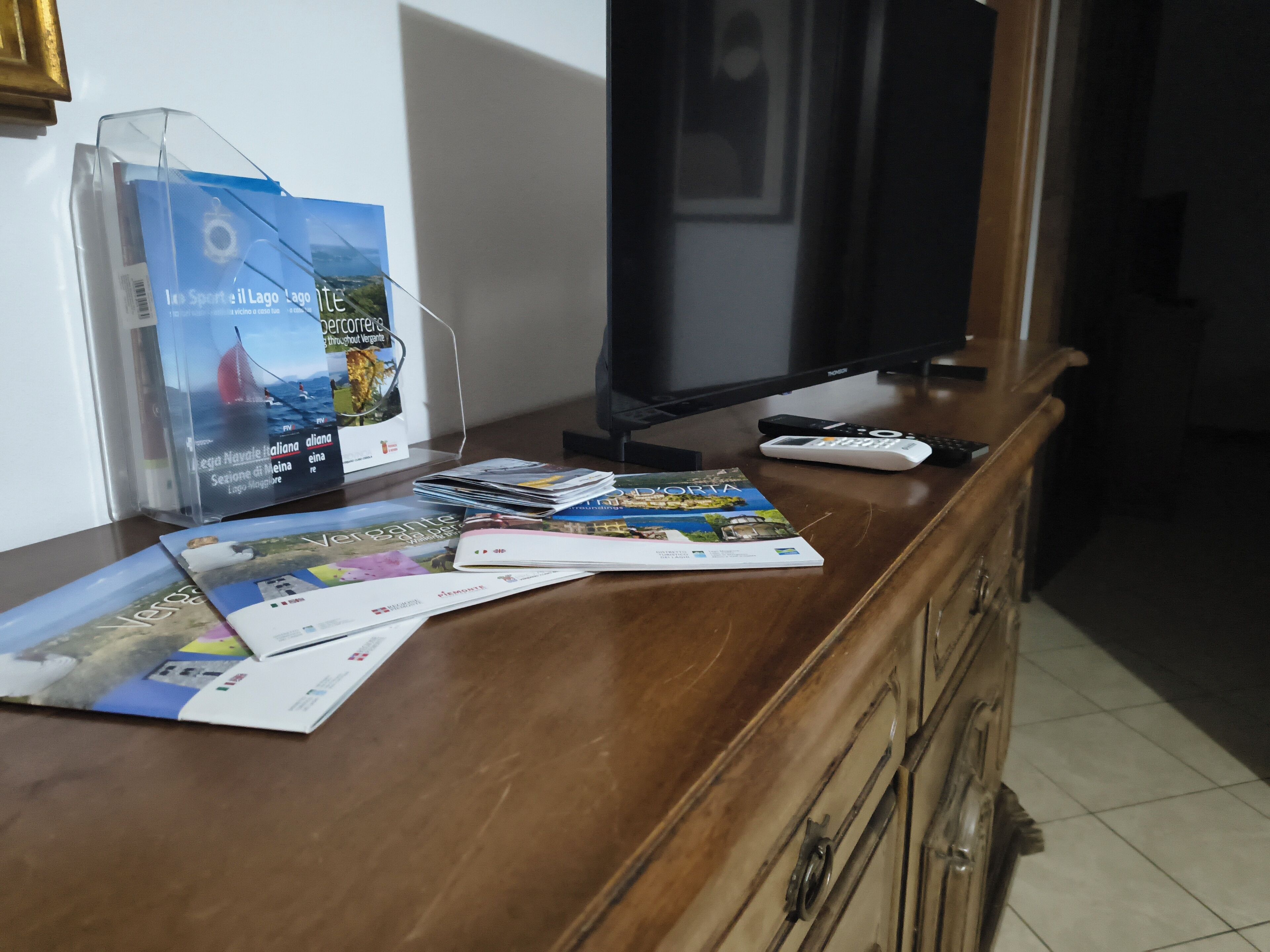 A wooden counter with magazines, a remote control, and a TV.