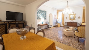 Un'area pranzo con tavolo, sedie, un lampadario e un televisore.