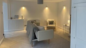 A modern bedroom with a bed, a chair, and a bedside table. - Samphire House (Cromer)
