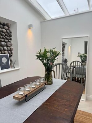 Un comedor moderno con una larga mesa de madera, candelabros y un jarrón de flores.