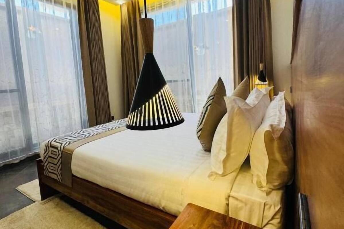 A modern hotel room with a large bed, a wooden nightstand, and a bedside table with a phone.