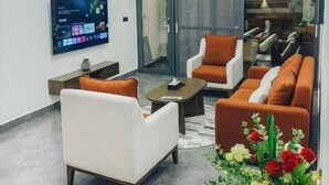 A modern living room with a flat-screen TV, comfortable seating, and a decorative plant. - Valonia Apartments  (Arusha)