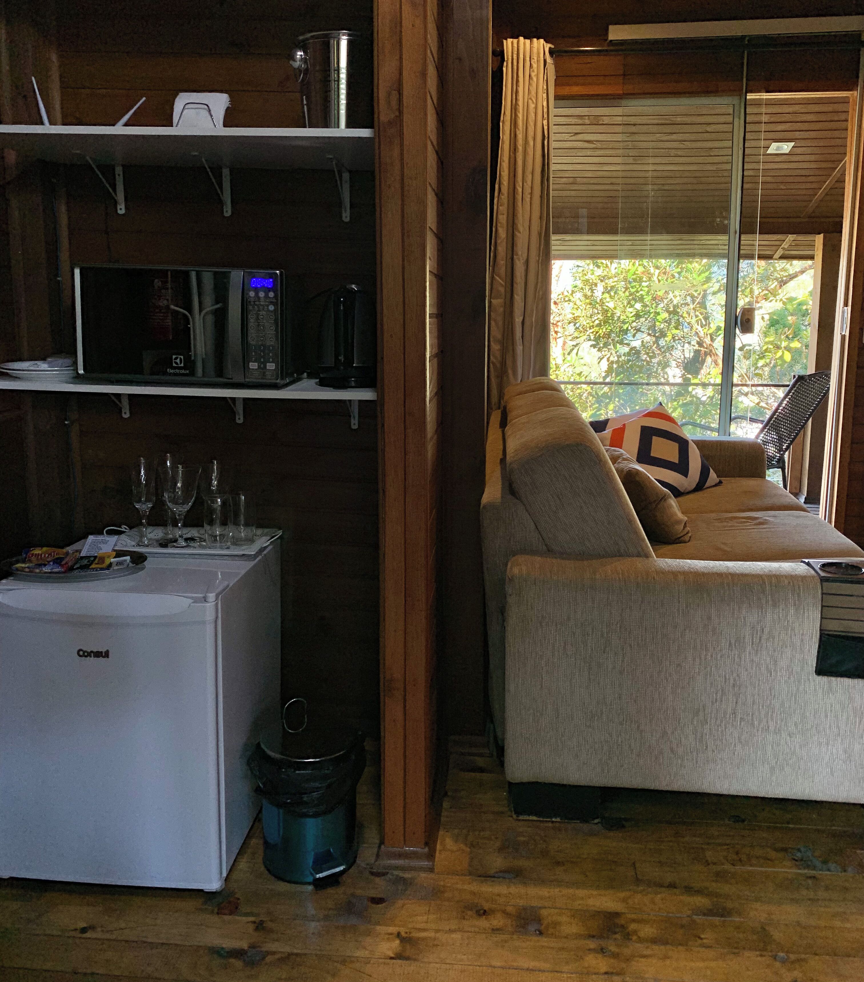 A compact room with a bed, a small kitchenette, and a window with curtains.