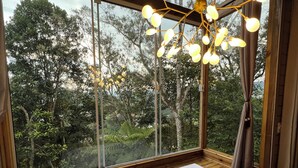 A wooden deck with a large window, a white hot tub, and a hanging light fixture. - Pousada Hinckel (Alfredo Wagner)
