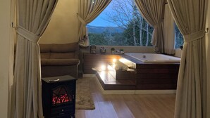 A cozy bedroom with a large window, a sofa, a bedside table, and a wooden ceiling. - Pousada Hinckel (Alfredo Wagner)