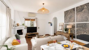 Un salon moderne avec une cheminée, un téléviseur et un coin repas avec une table mise pour deux personnes.