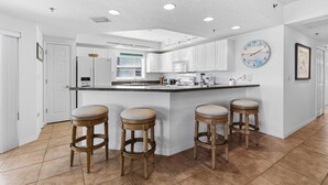 Una cucina moderna con mobili bianchi, una grande isola con sgabelli e un orologio a parete.