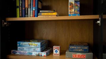 Une étagère contenant divers jeux de société et casse-têtes, notamment Scrabble, La Reine des neiges et le jeu de dames.