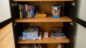 A bookshelf with books, board games, and decorative items. - The Downtown Post (Elizabethton)
