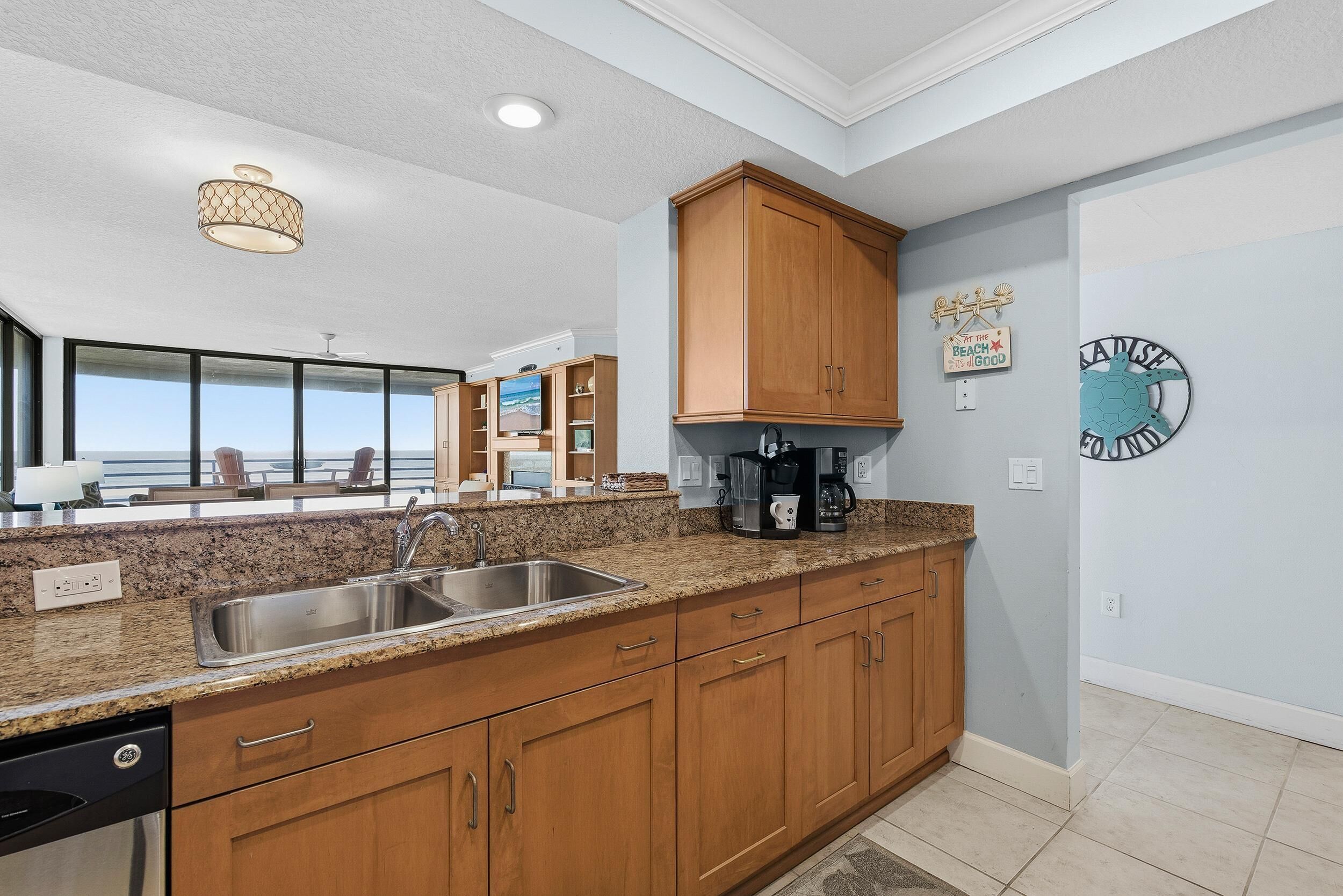 A modern kitchen with granite countertops, wooden cabinets, and a built-in dishwasher.