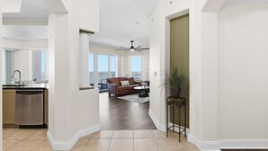 A spacious living area with a kitchen, a dining area, and a balcony with large windows. - Salida del Sol 1101 (Daytona Beach Shores)
