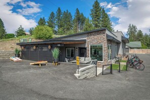 A modern building with a stone facade, a garage, and a paved driveway. - Waterfront home w/River access & Amazing views (Post Falls)