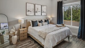 A bedroom with a large bed, bedside tables, a mirror, and artwork on the wall. - Waterfront home w/River access & Amazing views (Post Falls)