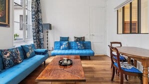 Ein modernes Wohnzimmer mit einem blauen Sofa, einem Holztisch und einem Esstisch mit Stühlen.