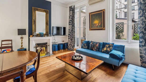 Ein Wohnzimmer mit einem blauen Sofa, einem Holztisch, einem Fernseher und einem Kamin.