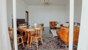 A dining area with a round table, chairs, and a chandelier. There is a sofa and a coffee table in the background. - Endless Charm by Monholiday (Monopoli)