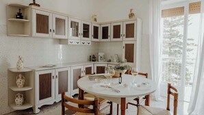 A kitchen with white cabinets, a round dining table, and a view of a balcony. - Endless Charm by Monholiday (Monopoli)