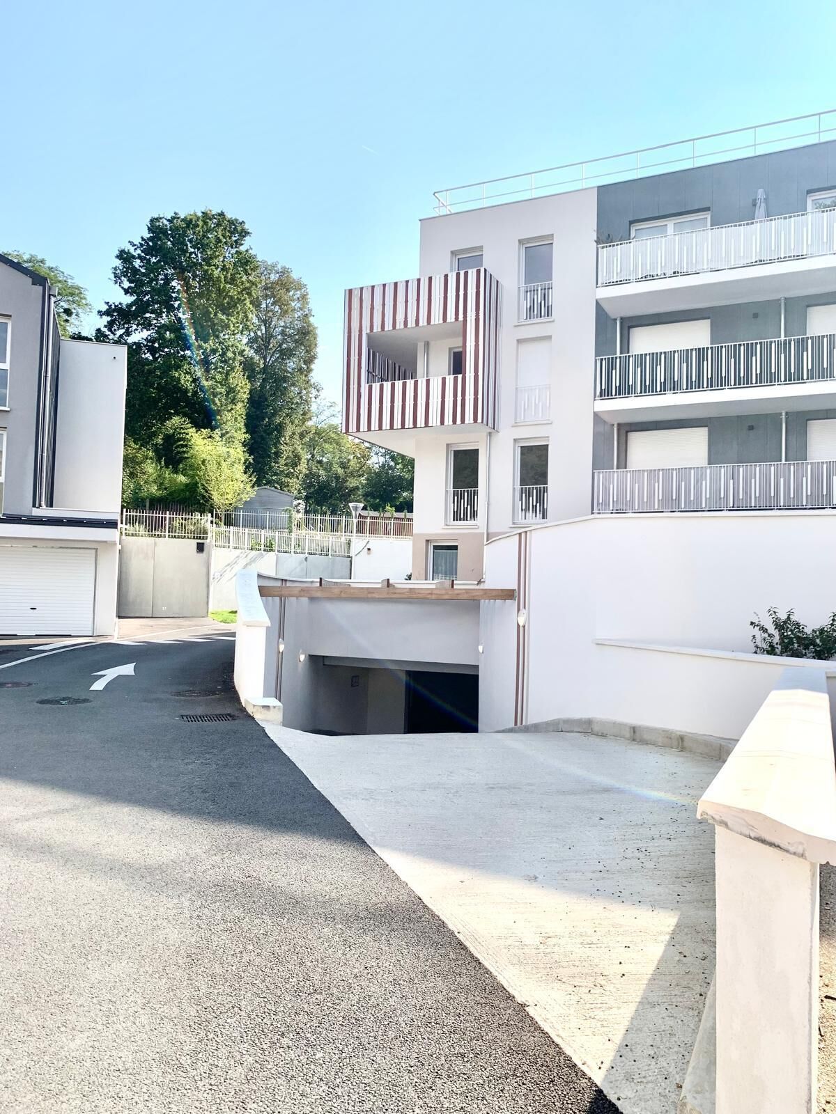 Een modern woongebouw met een plat dak, een balkon met een gestreept hekwerk en een hekpoort.